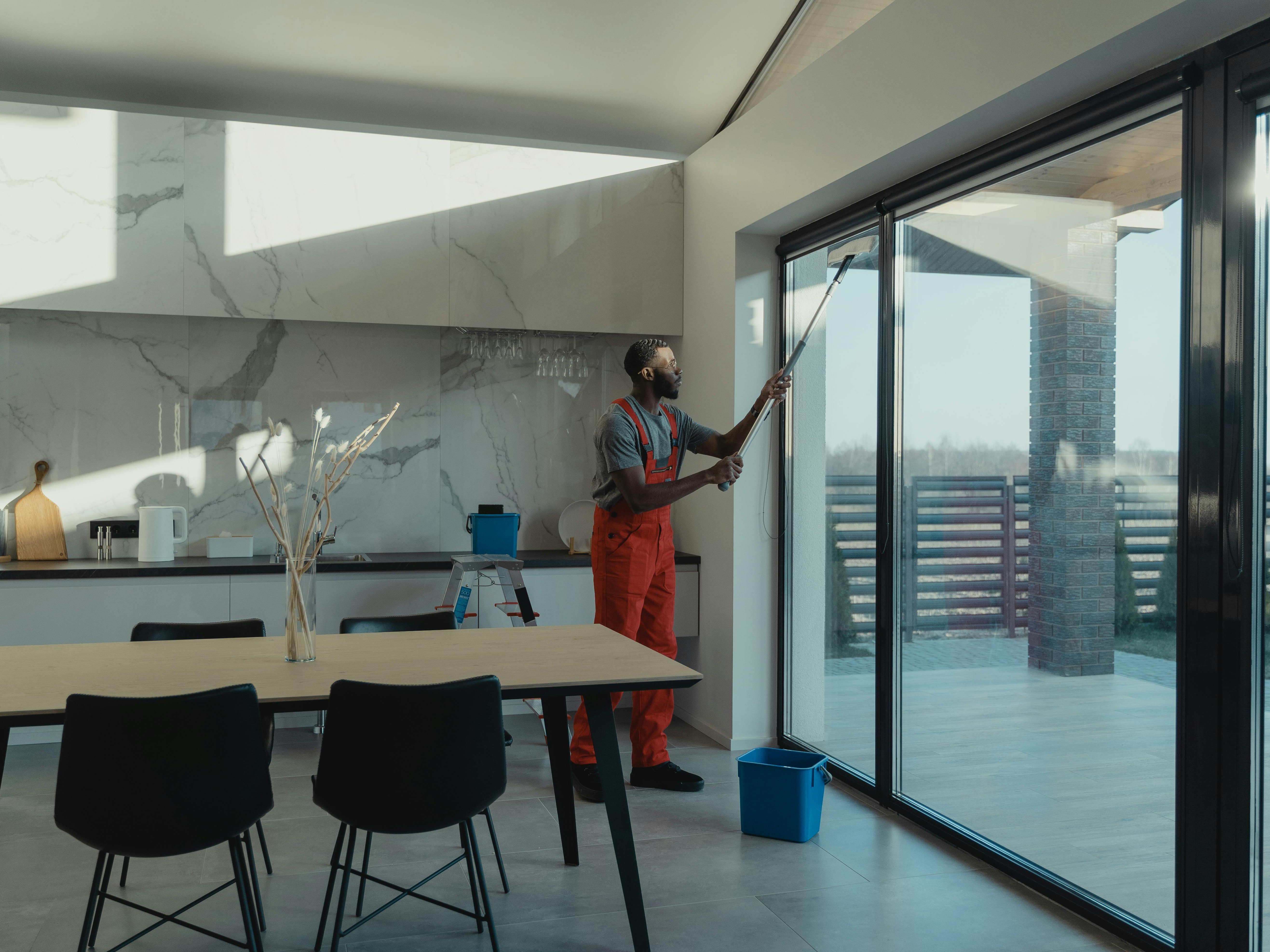 Mitarbeiter reinigt eine grosse Glasschiebetür in einem modernen Wohnraum