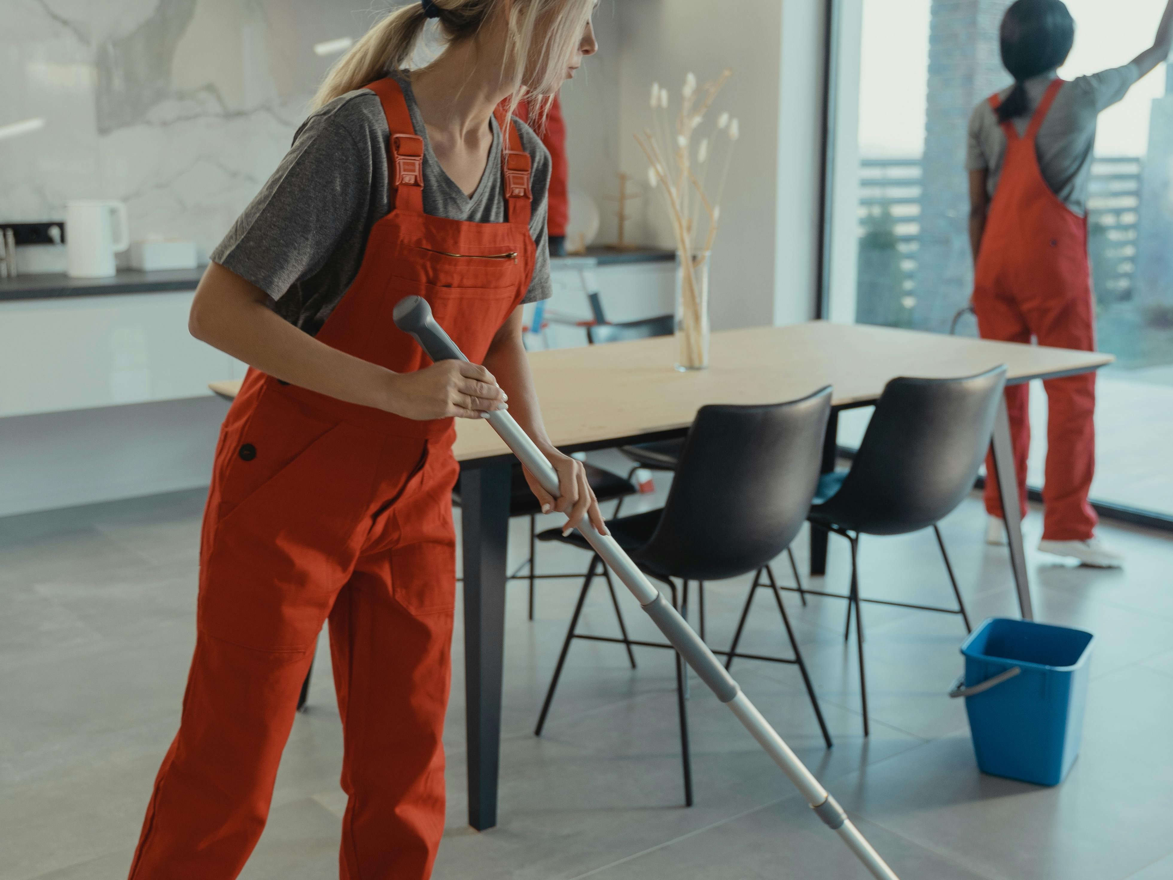 Reinigungsteam wischt den Boden und putzt Fenster in einem modernen Wohnraum